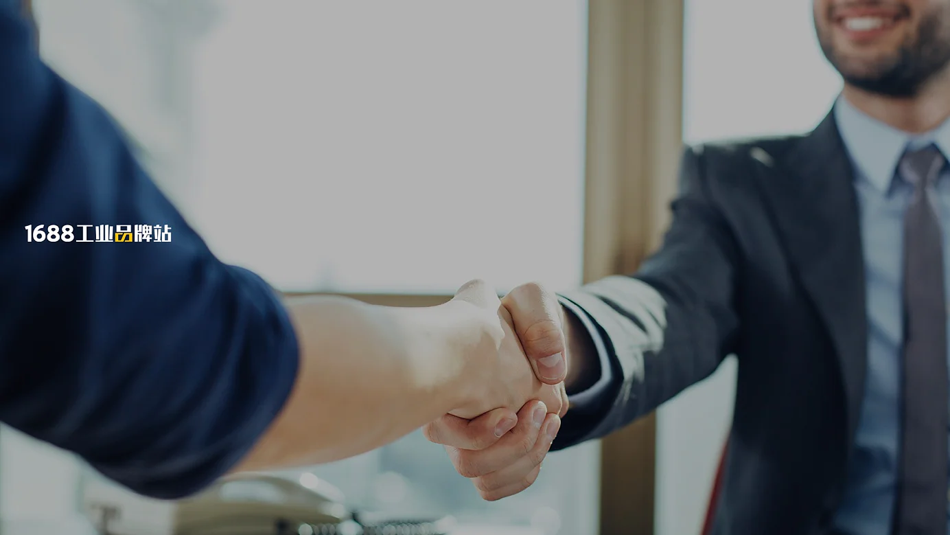 Two people are shaking hands over a desk with documents, charts, and a tablet on it. Both are dressed in business attire. The lighting suggests a daytime office setting. (This text has been generated by AI)