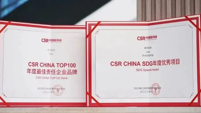 Two award certificates displayed side by side. The left one is titled CSR China Top 100, and the right one is CSR China SDG Special Award. Both certificates have text in Chinese and English, featuring red borders secured with tesa tape and the CSR logo. (This text has been generated by AI)